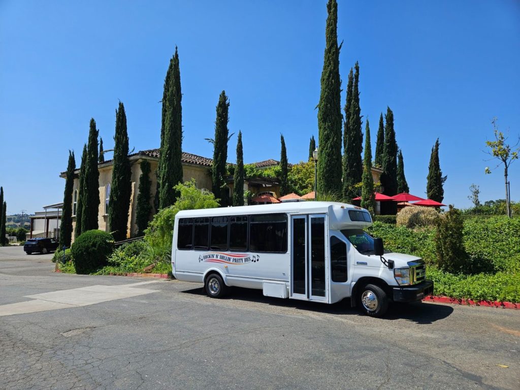 A white bus parked in front of some trees