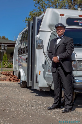 A man in a suit and hat standing next to a bus.