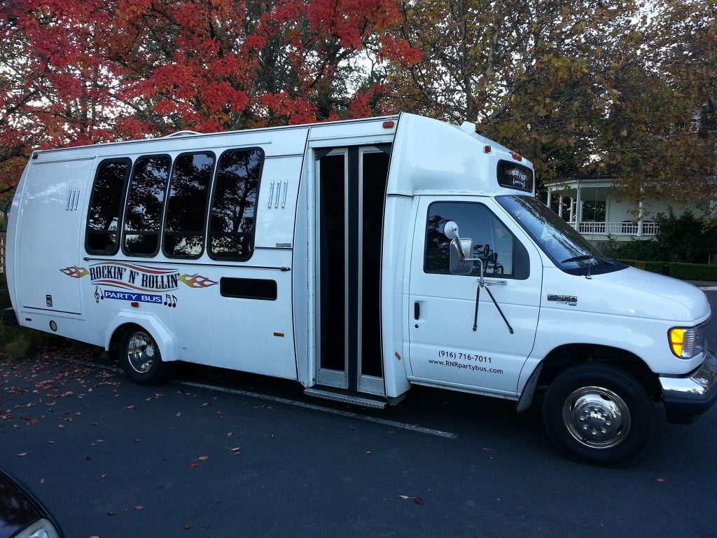 A white bus with people in it parked on the side of the street.