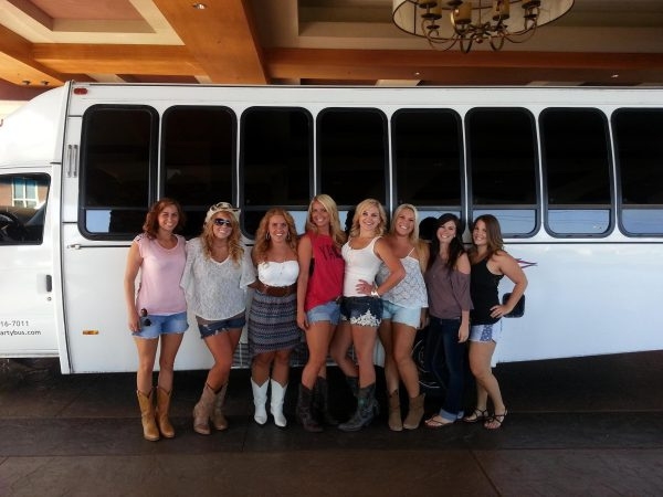 A group of women standing in front of a white bus.