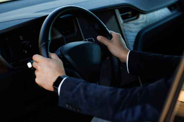 A person in a suit is holding the steering wheel of their car.