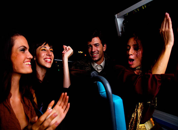 A group of people on a bus with one man clapping.